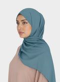 HIJABI LONDON moss chiffon hijab in a dusty blue colour, draped elegantly on a model.